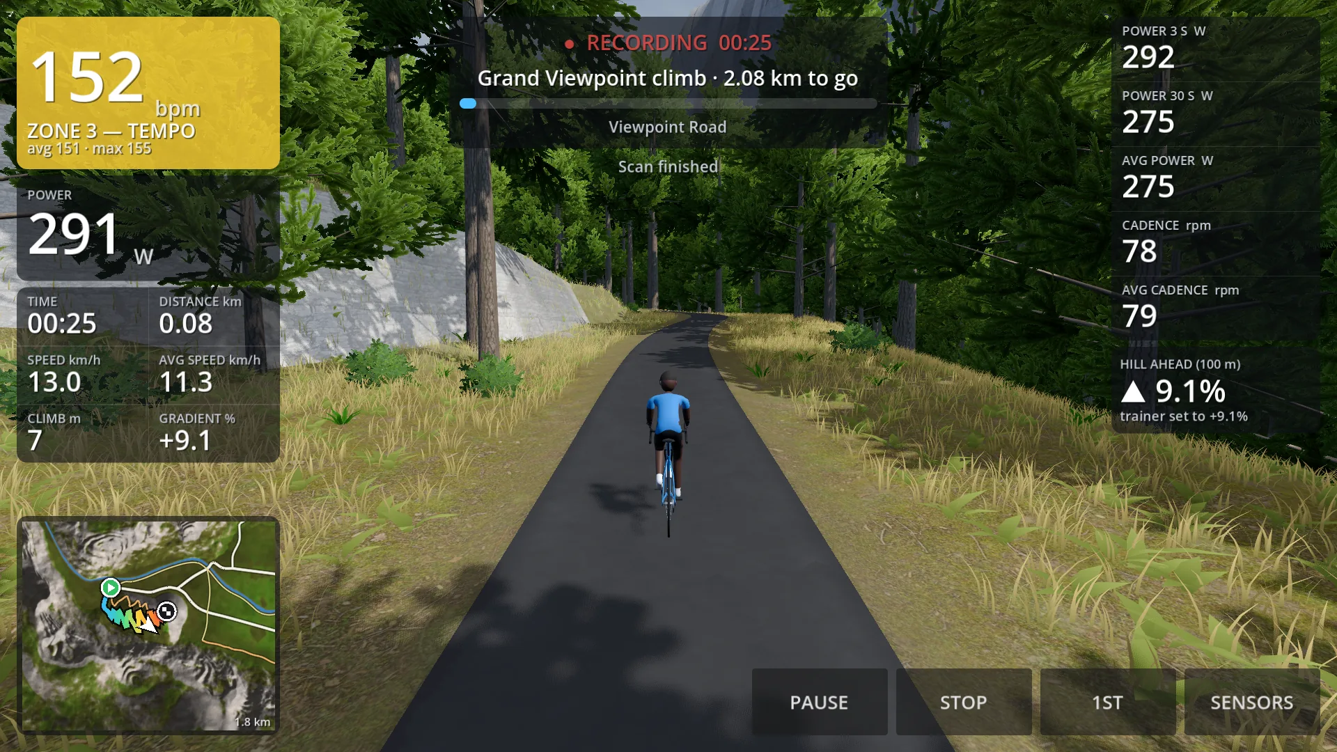 A rider on a single-track lane climbing through pine wood in the valley, seen from behind, with the gradient ahead on the screen.